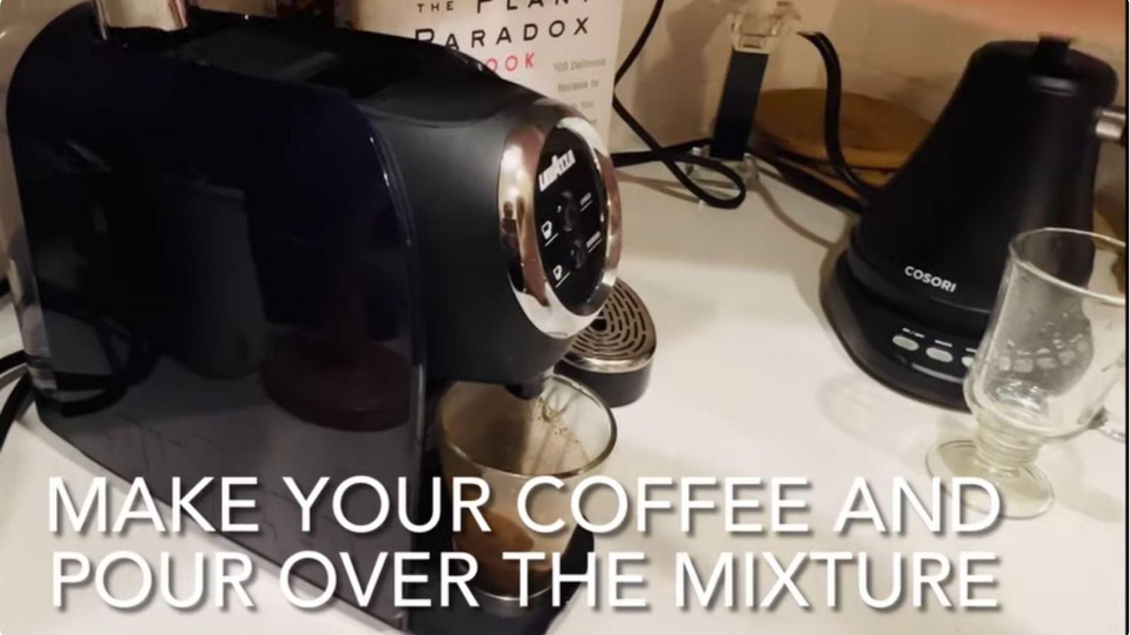 A Lavazza pod coffee machine brewing into a glass cup on a counter with a Cosori frother and text reading "Make your coffee and pour over the mixture."