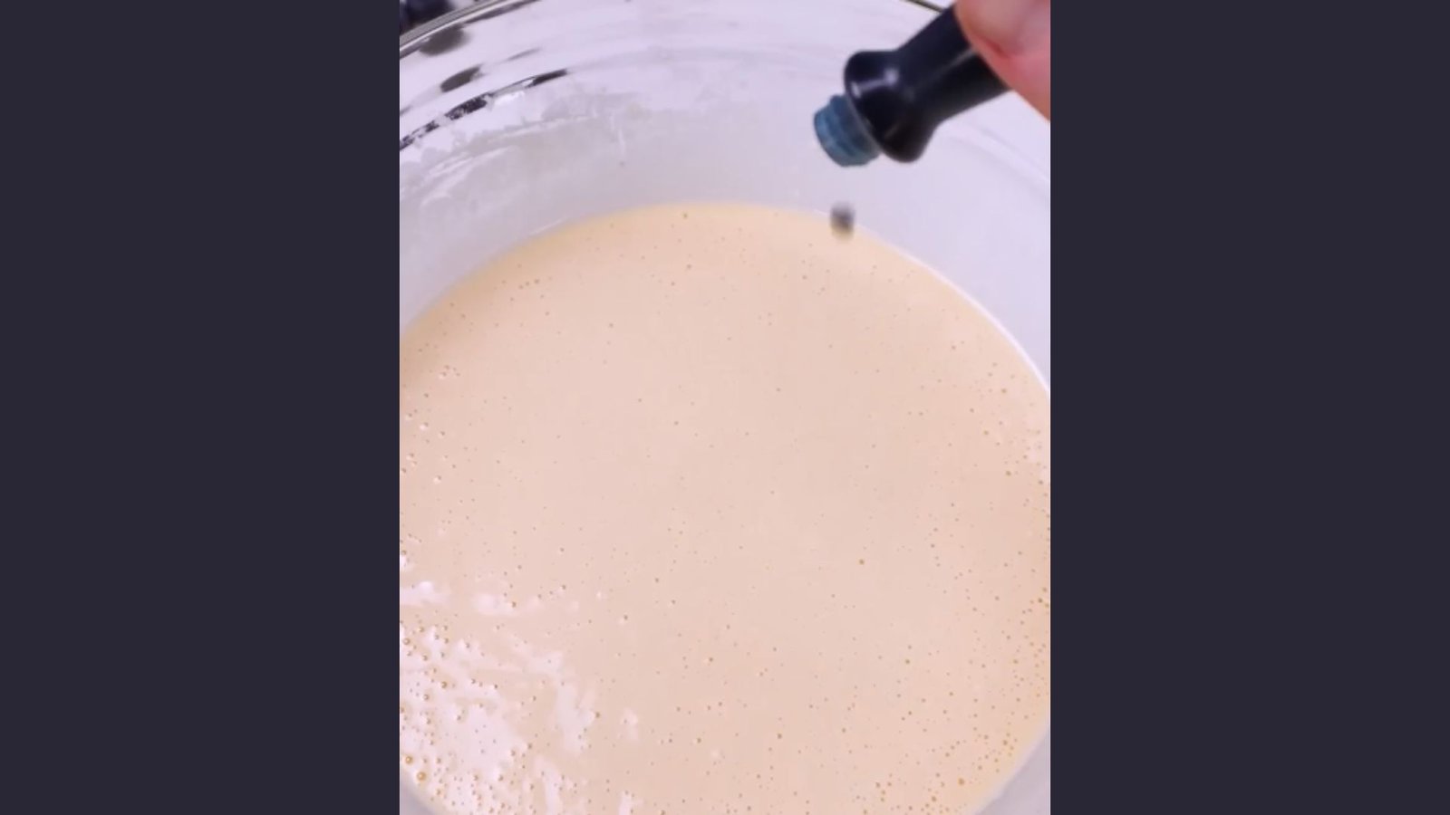 Blue food coloring dropped into pale waffle batter in glass mixing bowl to create blue waffle color
