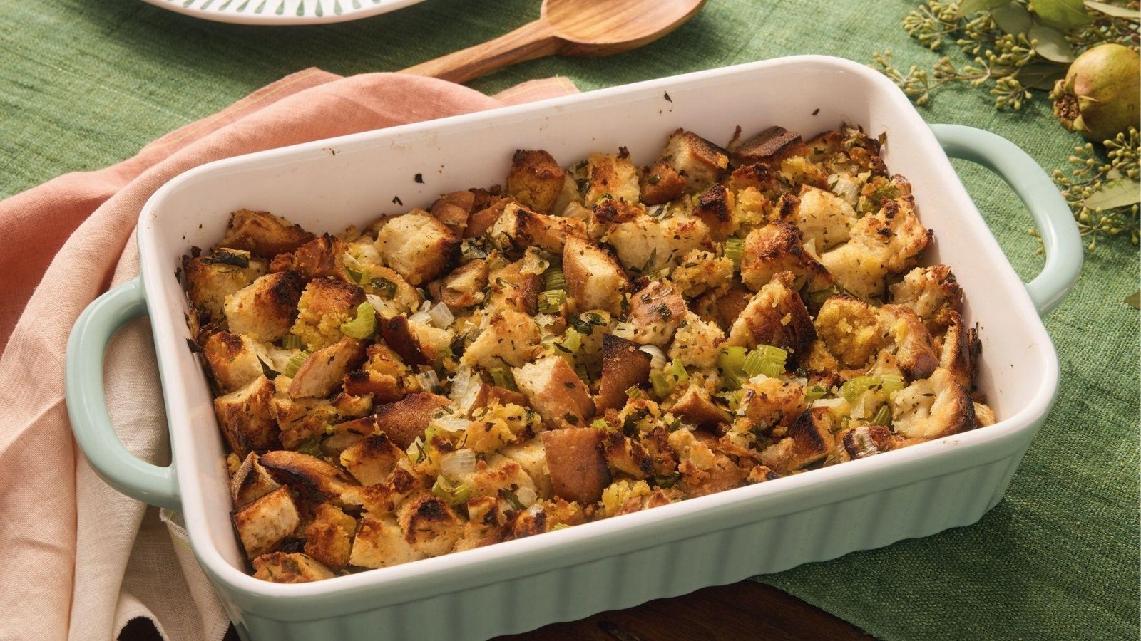 Chunky cornbread dressing with toasted bread cubes and celery in mint-rimmed baking dish
