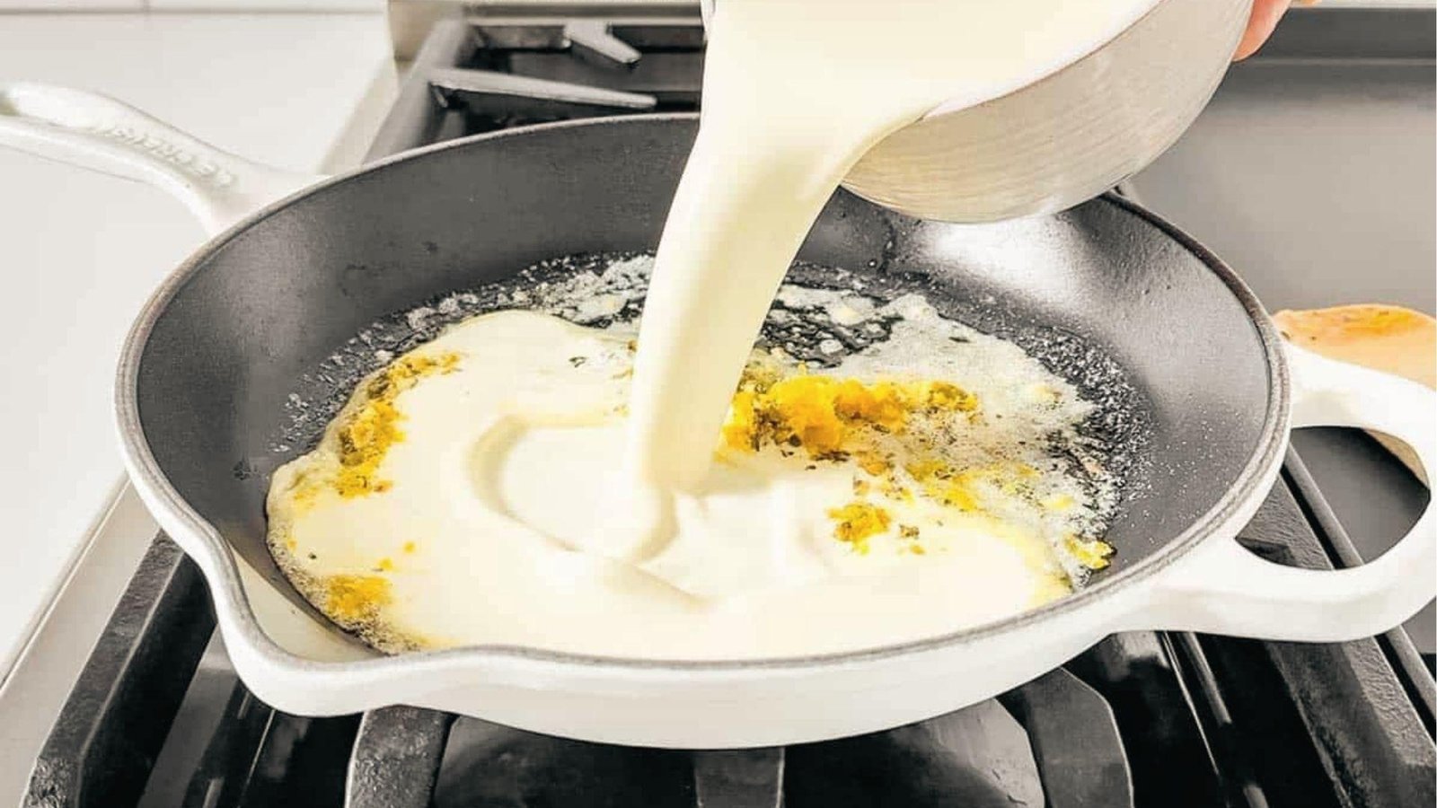 Cream poured into skillet with melted butter and garlic, starting pasta cream sauce on stovetop