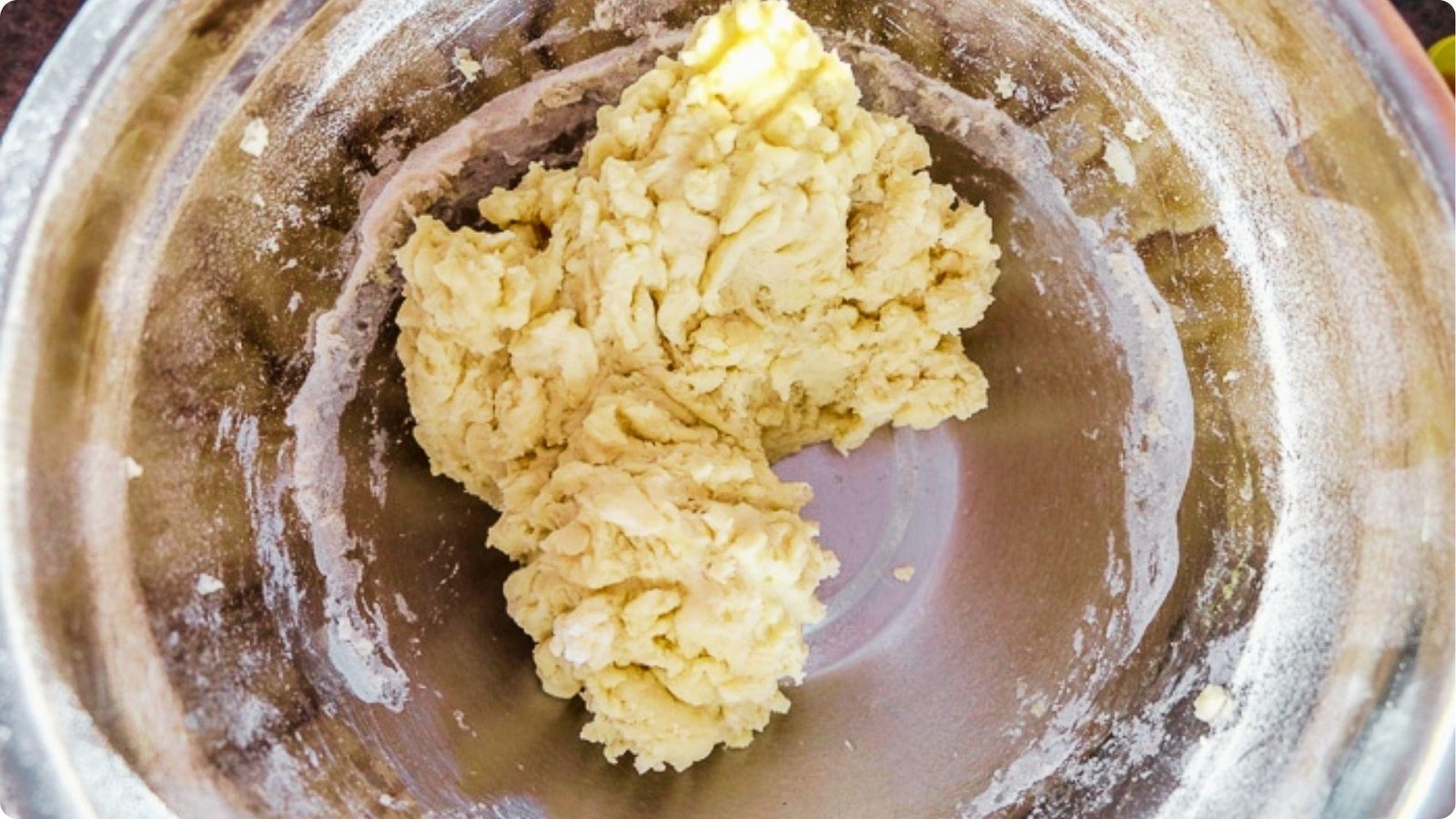 Overhead view of thick German coffee cake dough in a stainless steel mixing bowl.
