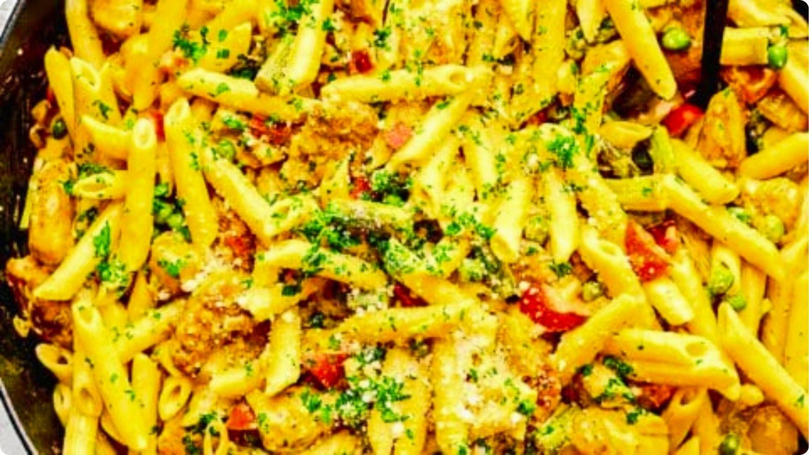 Skillet of finished chipotle penne pasta mixed with chicken, peas, and red peppers in creamy sauce.