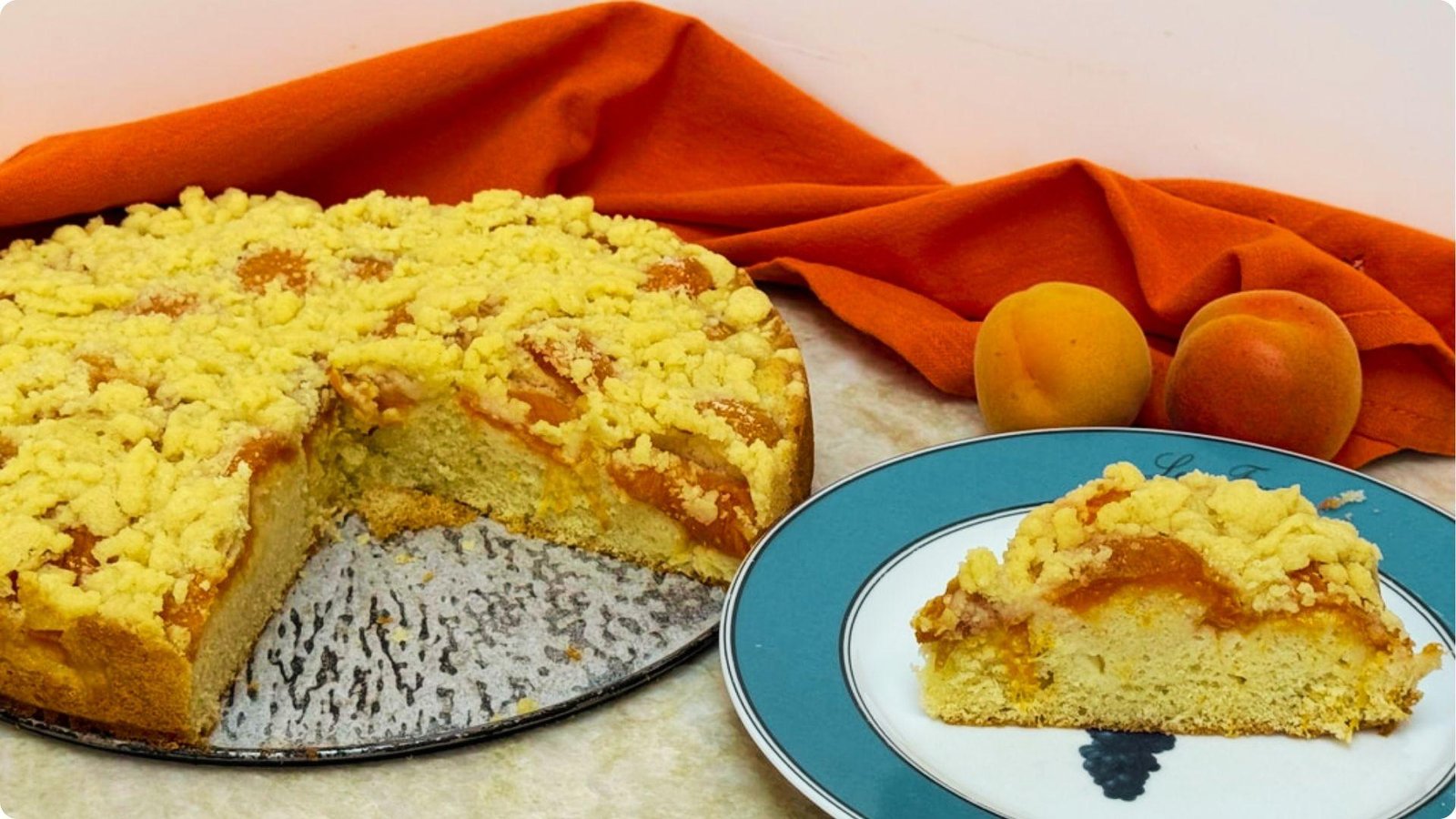 A round german coffee cake with a slice served on a blue plate beside it.