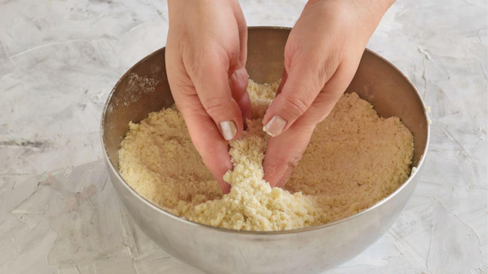 Hands rubbing butter into flour to form sandy crumbs for tender pate sablee pastry base