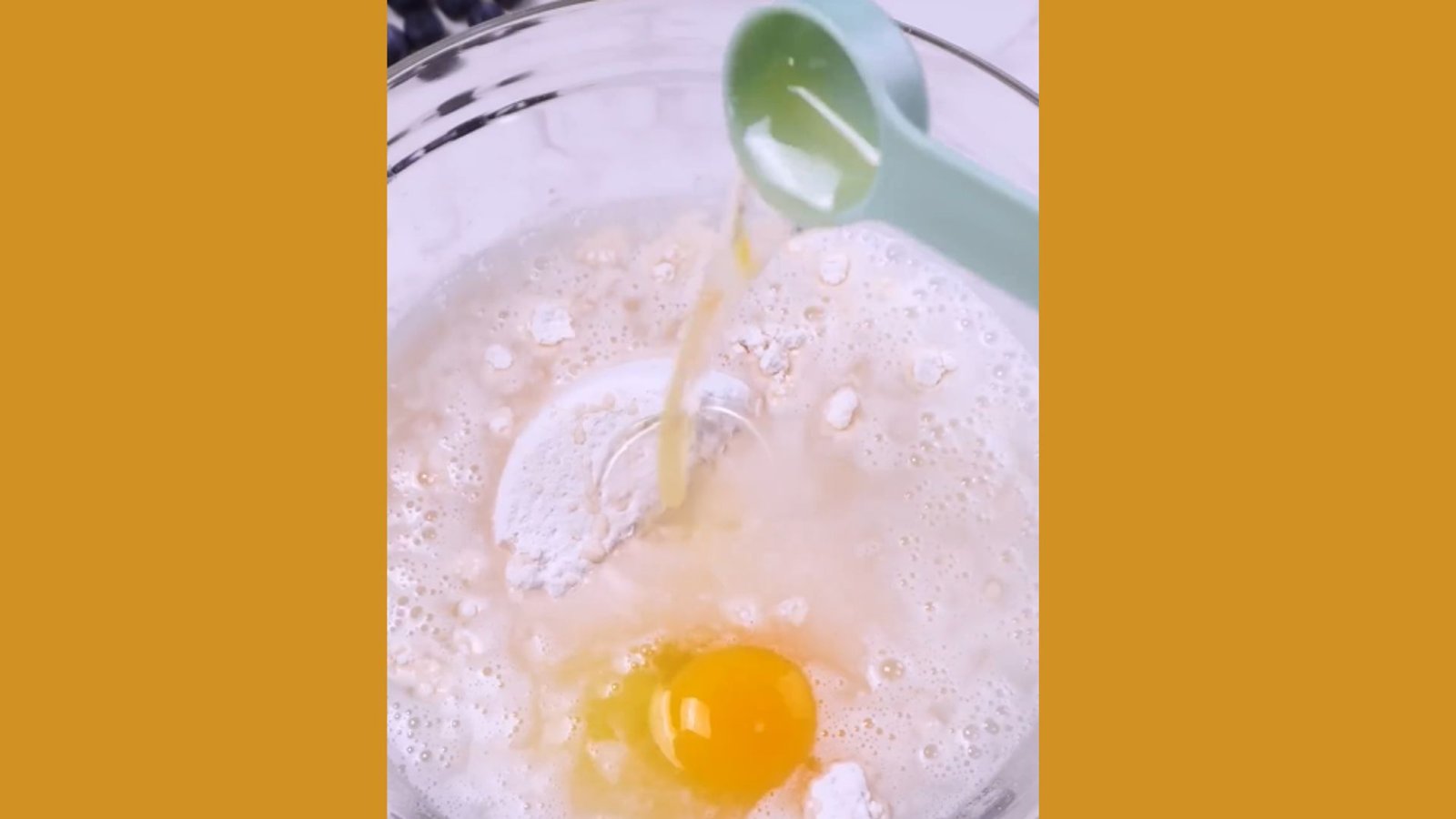 Oil poured from measuring spoon into waffle batter with egg and flour in glass bowl