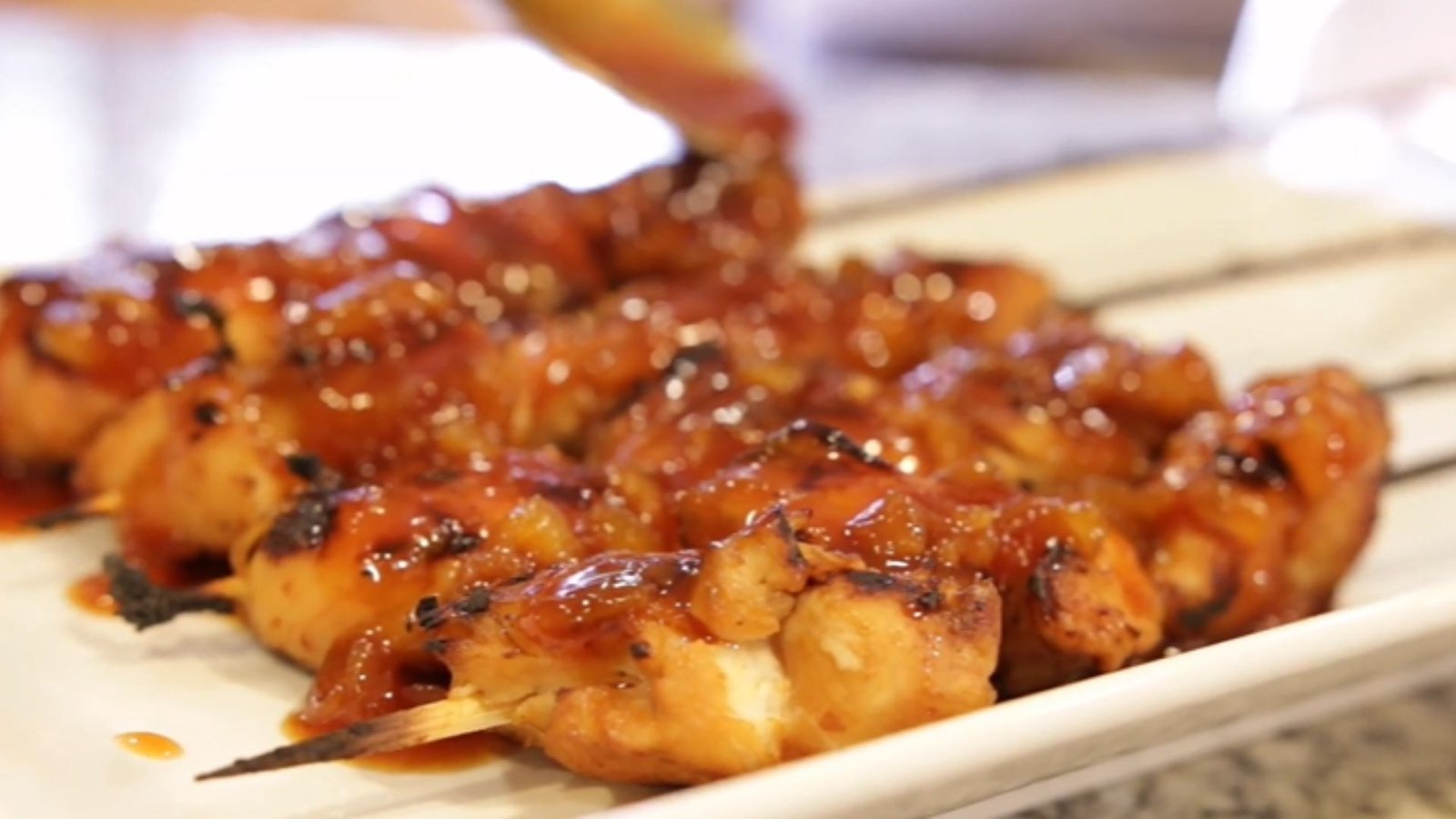 Glossy Hawaiian BBQ sauce glazed grilled chicken skewers on a white plate, served hot with pineapple flavor