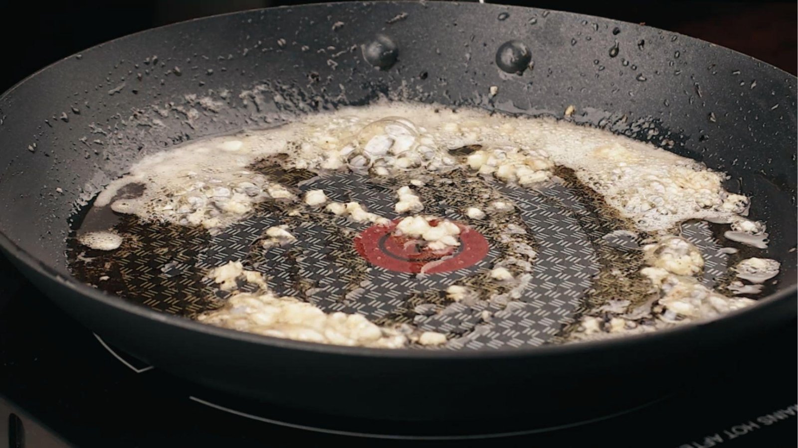 Minced garlic sizzling in melted butter in nonstick pan, first step for flavorful cream sauce