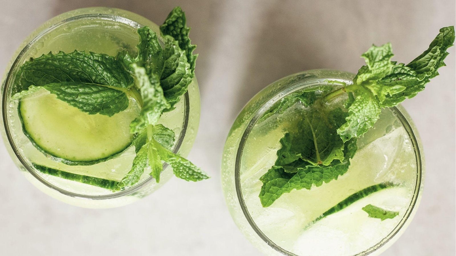 Overhead view of two glasses of iced cucumber mint agua fresca garnished with mint and cucumber rounds