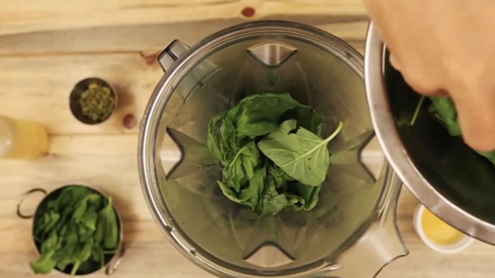 Fresh basil leaves added into a grinder or food processor as the base of pumpkin seed pesto recipe.
