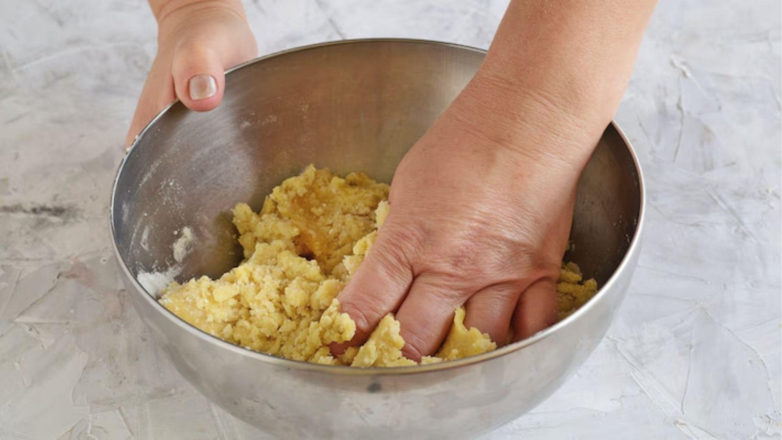 Hand pressing pate sablee dough into crumbs, bringing pastry together before chilling dough