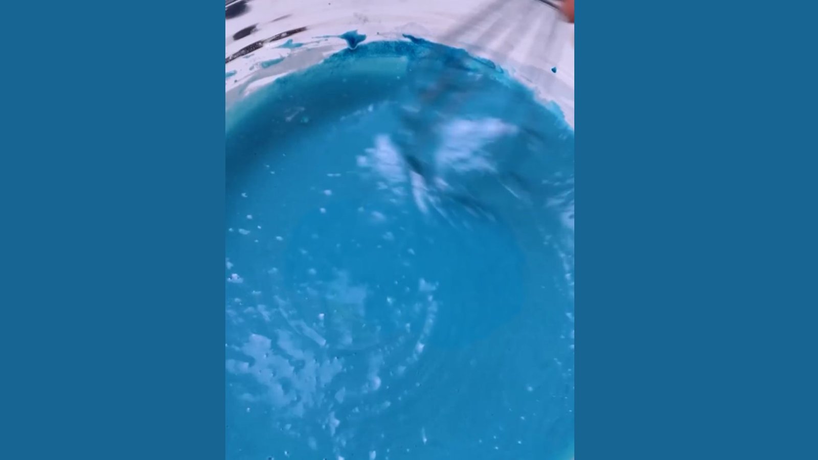 Vibrant blue waffle batter being whisked in clear glass bowl creating smooth consistency for cooking