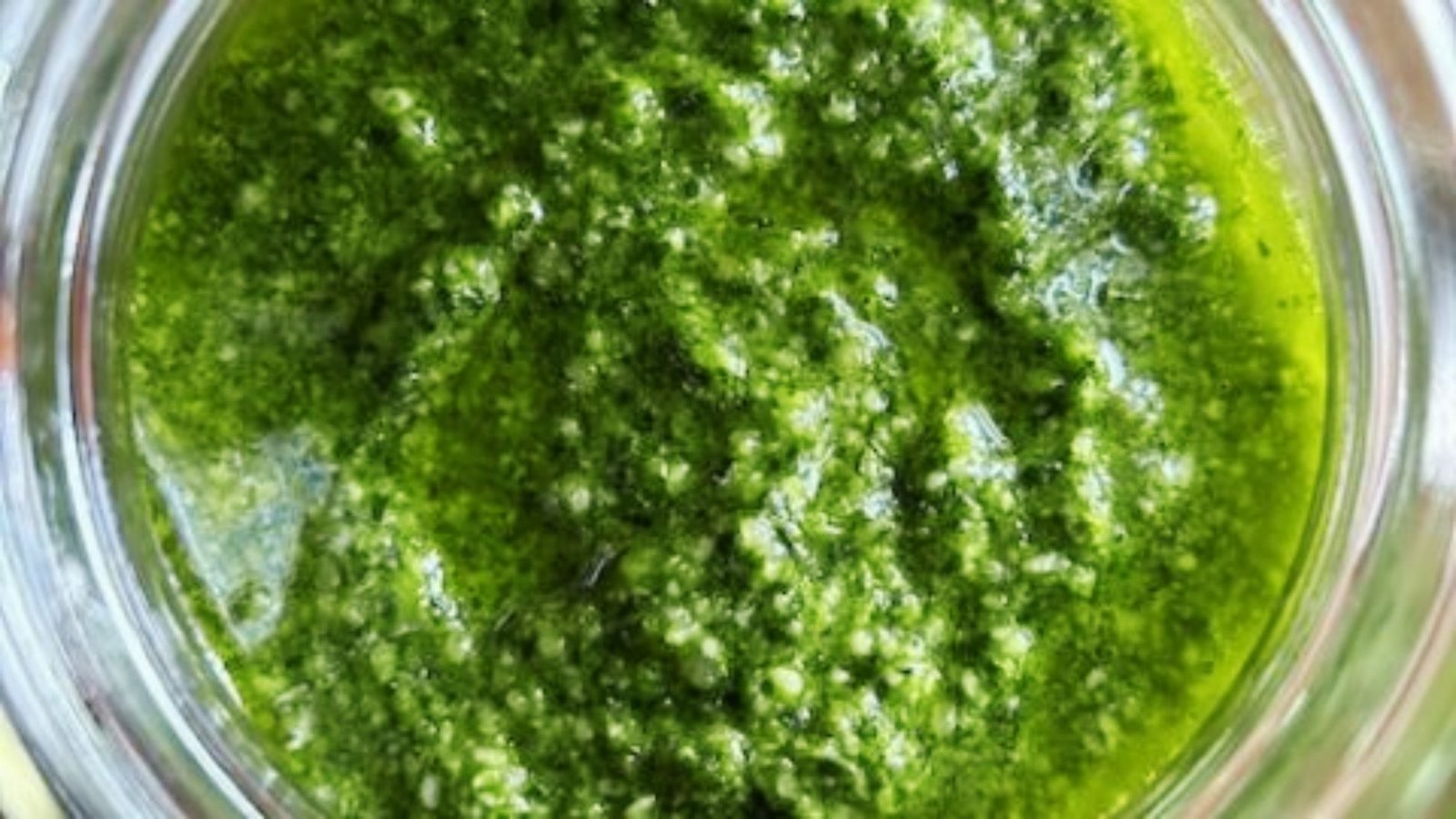 Close-up of creamy green pumpkin seed pesto in glass jar showing thick textured consistency