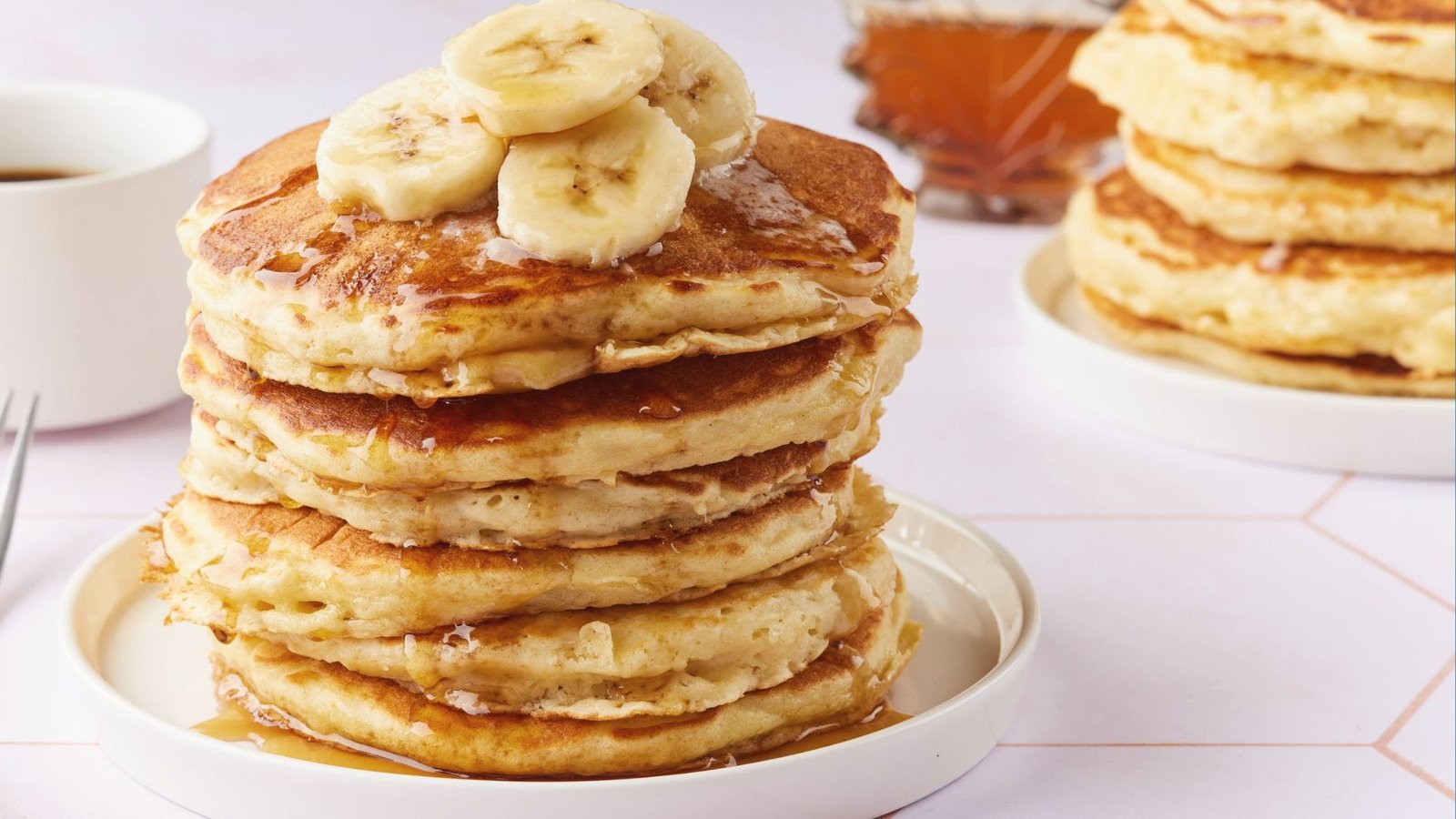 fluffy Banana yogurt pancakes topped with banana, honey, syrup served in a plate.