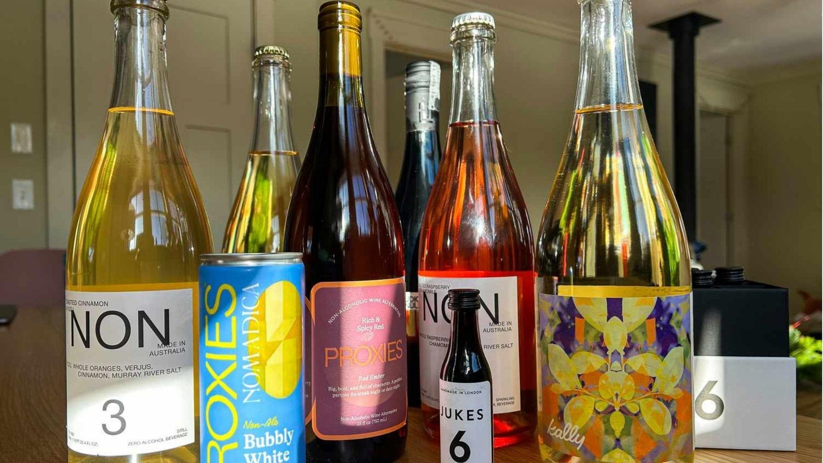 A collection of six non-alcoholic wine alternative bottles including NON, Proxies, and Jukes brands displayed on a table.
