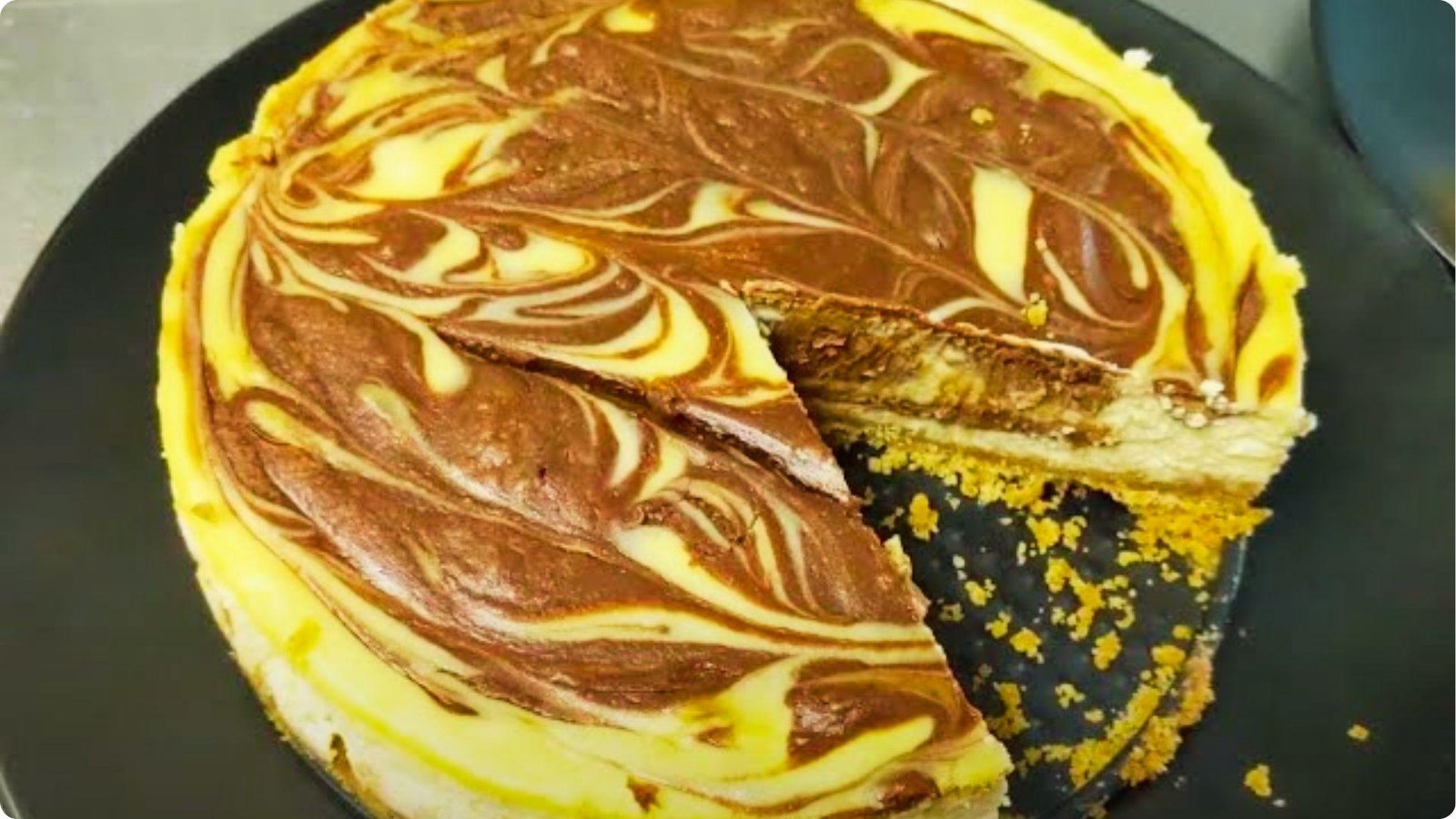 Top-down view of a 6-inch chocolate marble cheesecake with dramatic dark cocoa swirls on the pale vanilla filling.