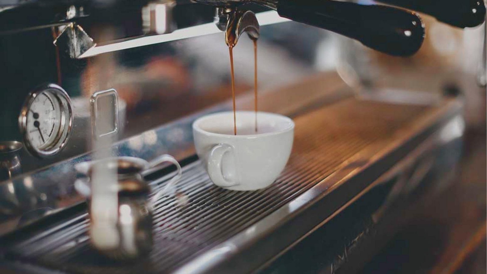 Double shot of espresso pouring into a white ceramic cup from a professional machine for a Mezcal Espresso Martini base.