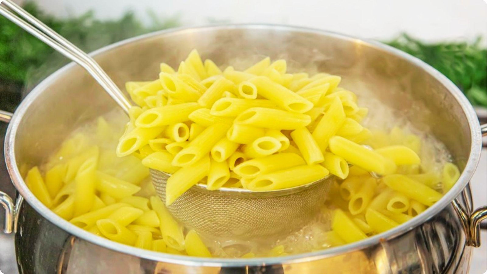 Cooked penne pasta being lifted from a stainless steel pot of boiling water using a slotted ladle.