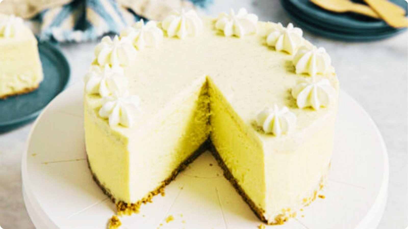 A 6-inch vanilla cheesecake with one slice removed sits on a white cake stand.