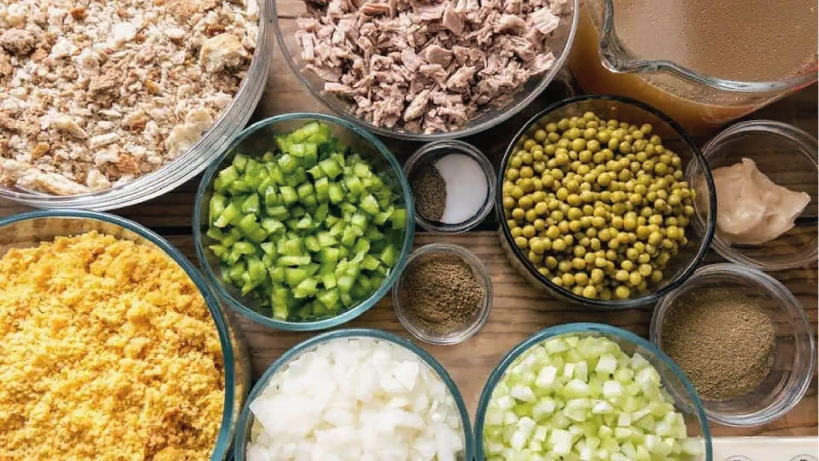 Prepped cornbread dressing ingredients crumbled bread, veggies, spices, broth, and meat bowls