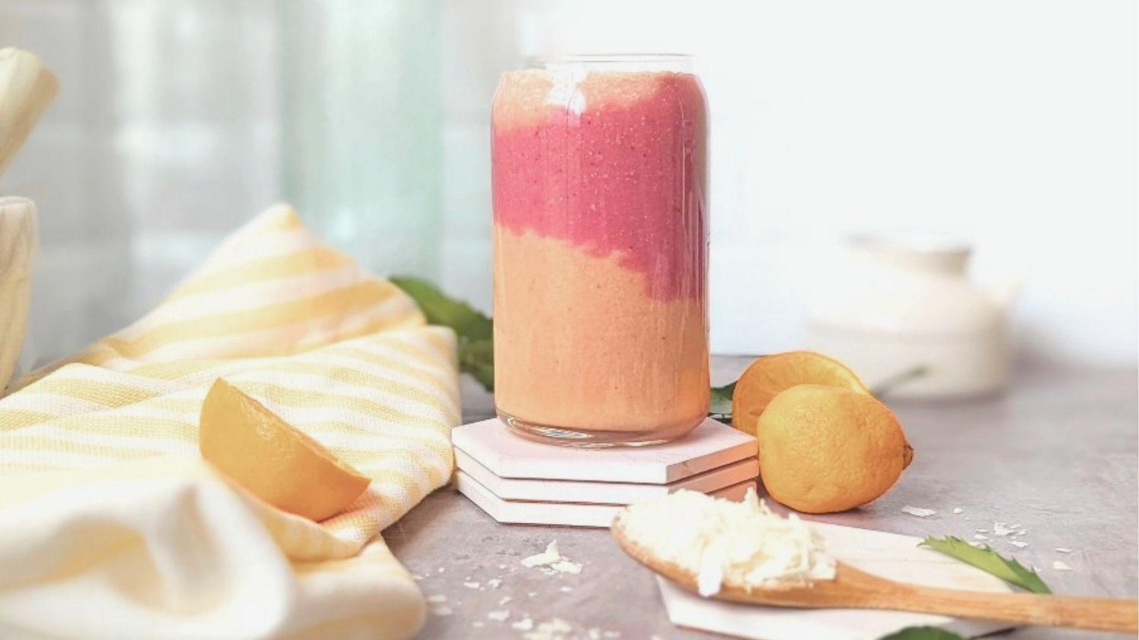 Layered Bahama Mama Tropical Smoothie in a clear can-shaped glass with pink strawberry and orange pineapple layers.