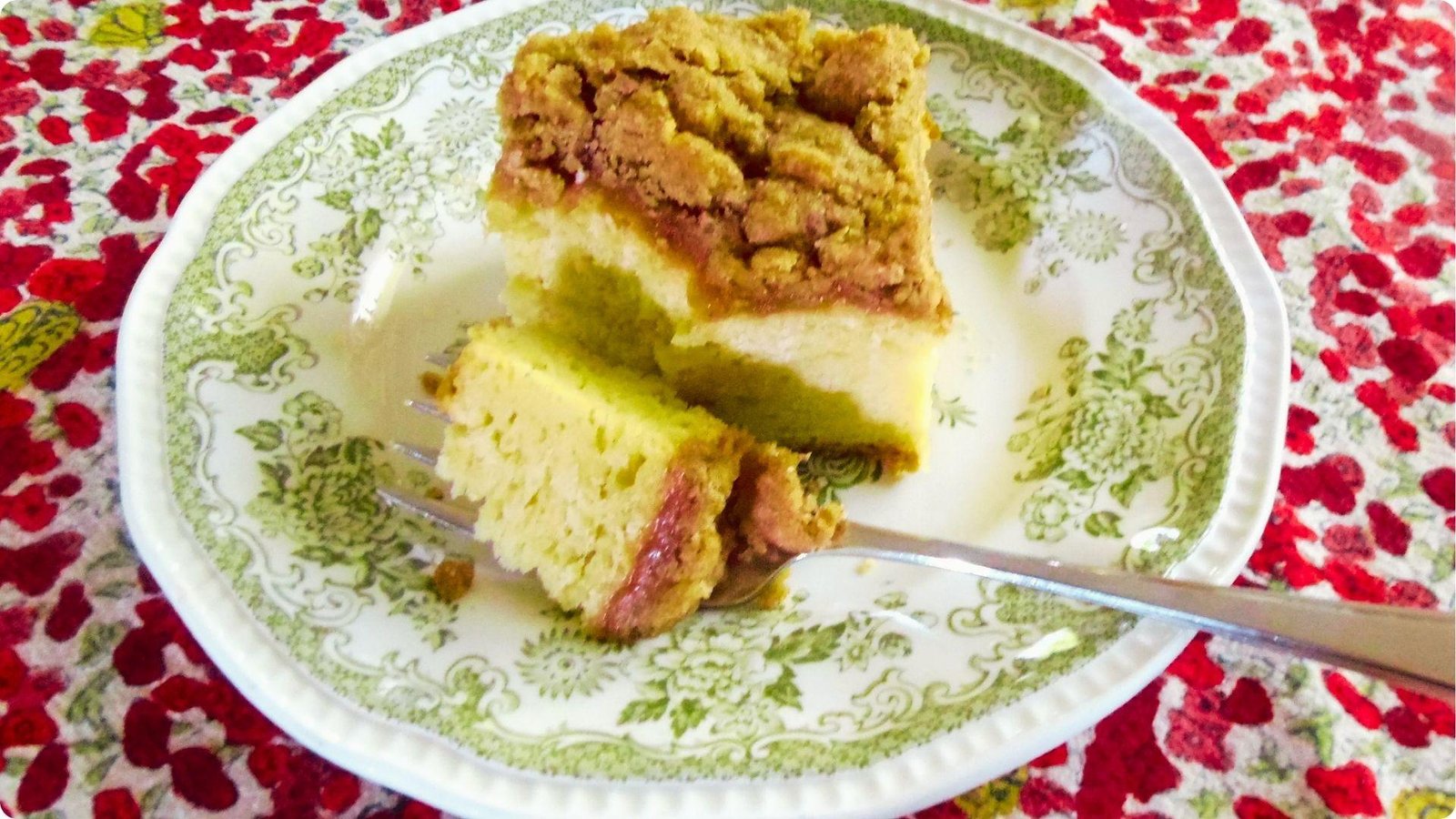 A slice of German coffee cake with cinnamon streusel and a fruit layer served on a floral vintage plate.