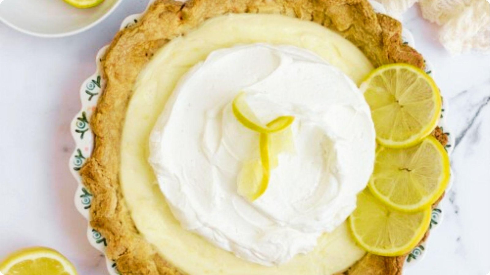 Overhead view of a sour cream lemon pie with a rustic golden crust in a decorative ceramic dish.