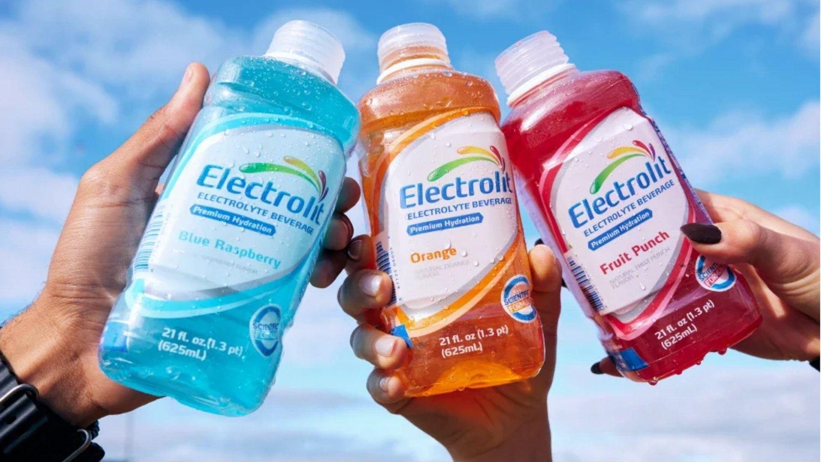 Three hands holding Electrolit electrolyte bottles in Blue Raspberry, Orange, and Fruit Punch flavors against a blue sky.
