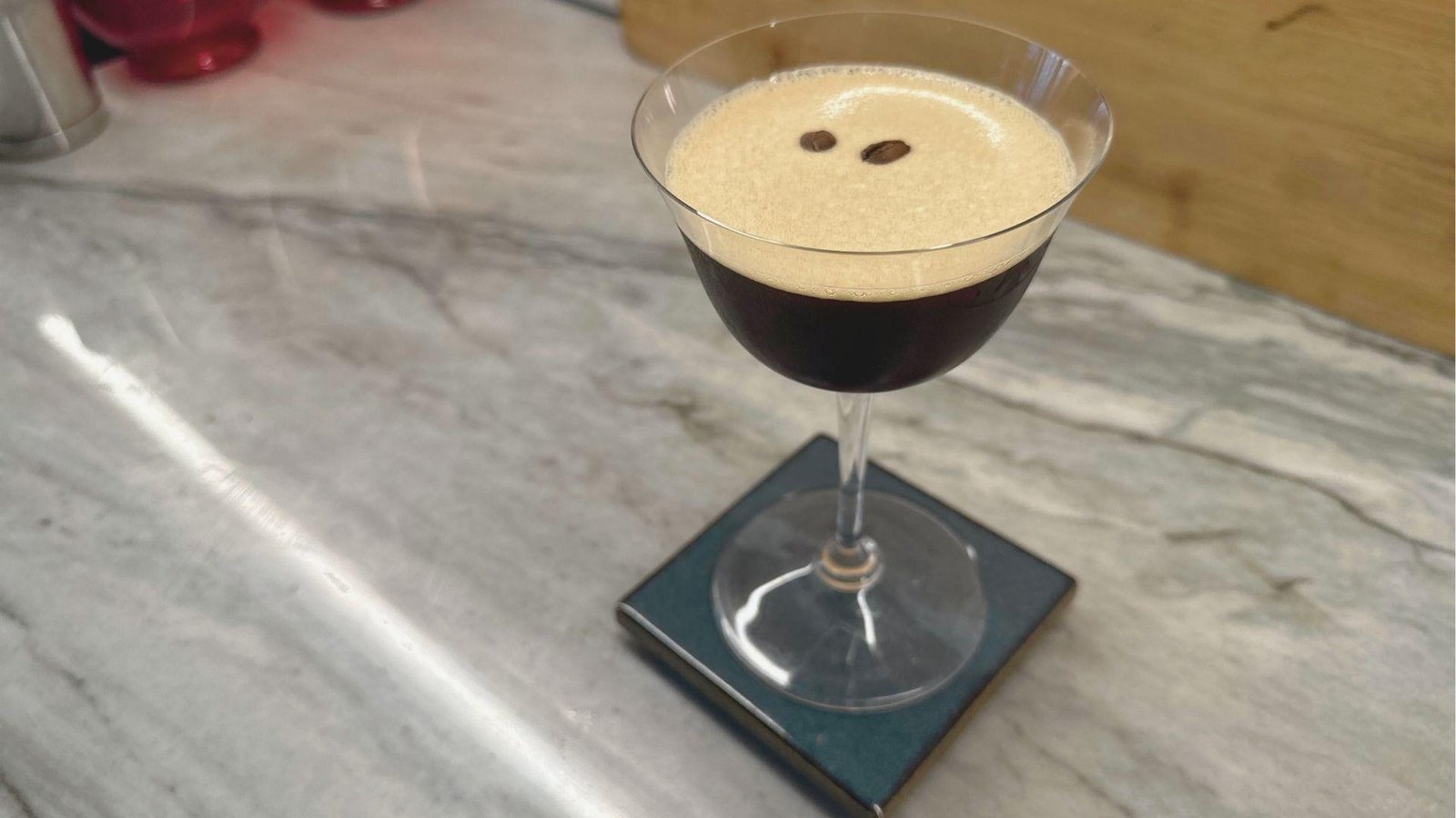 Classic Mezcal Espresso Martini served in a Nick & Nora glass with thick tan foam and two coffee bean garnish.