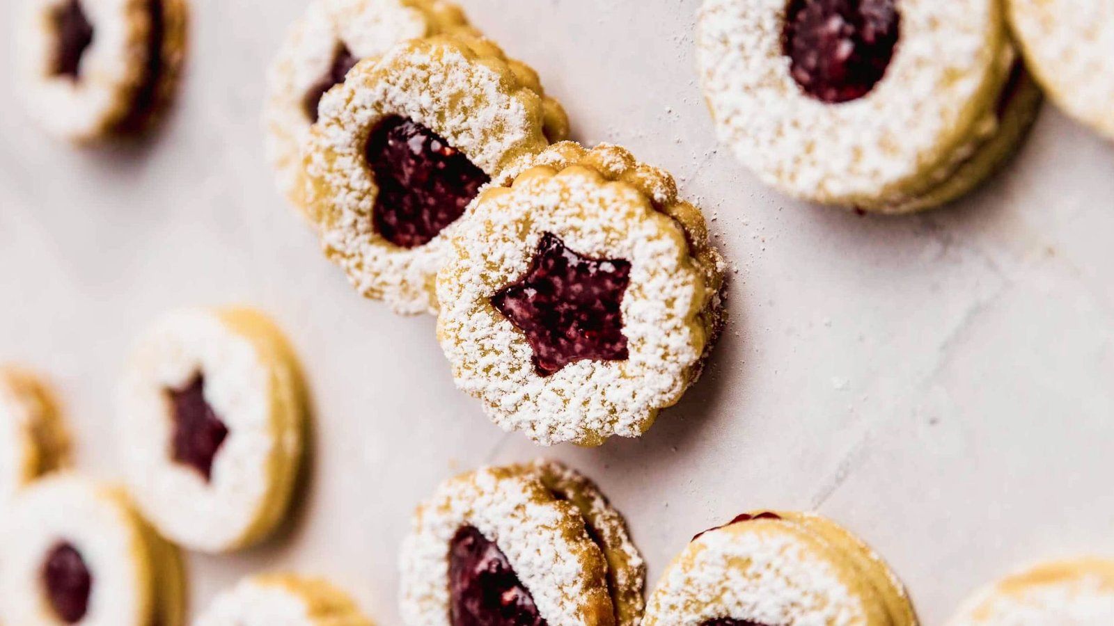 Homemade Linzer cookies dusted with powdered sugar and filled with jam, ready to serve and enjoy.