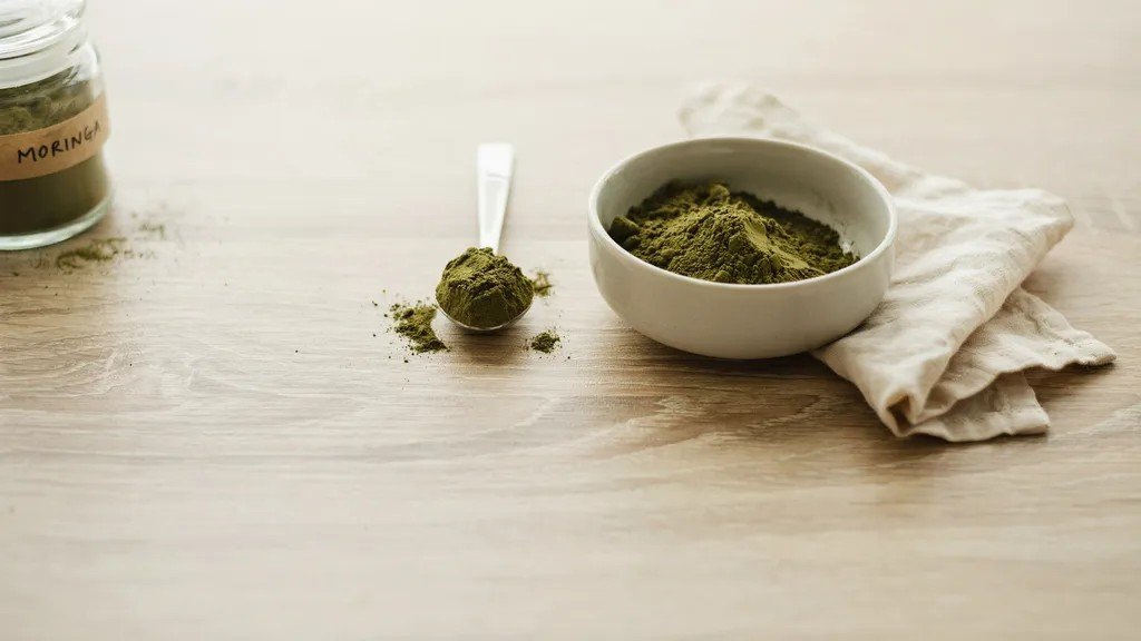 measuring moringa powder with a tablespoon to show correct beginner dosage.