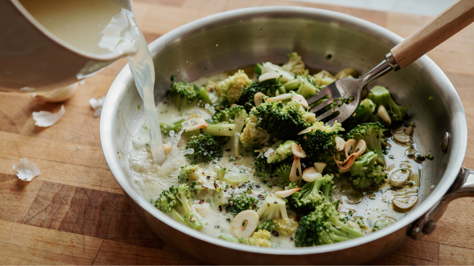 broccoli being mashed into garlic and olive oil with pasta water to create a creamy sauce.
