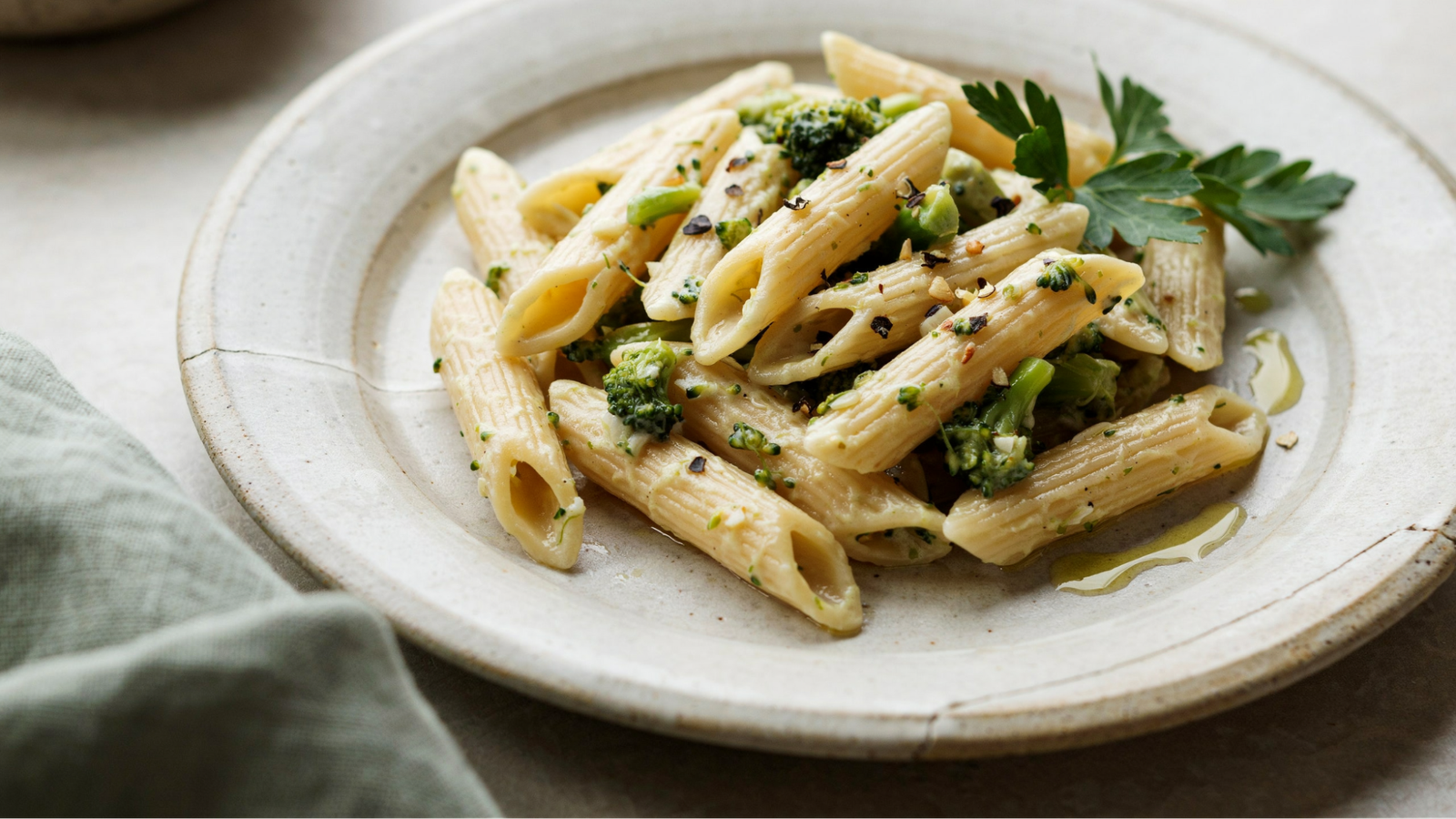 short pasta coated in creamy broccoli garlic sauce showing texture made from mashed broccoli.
