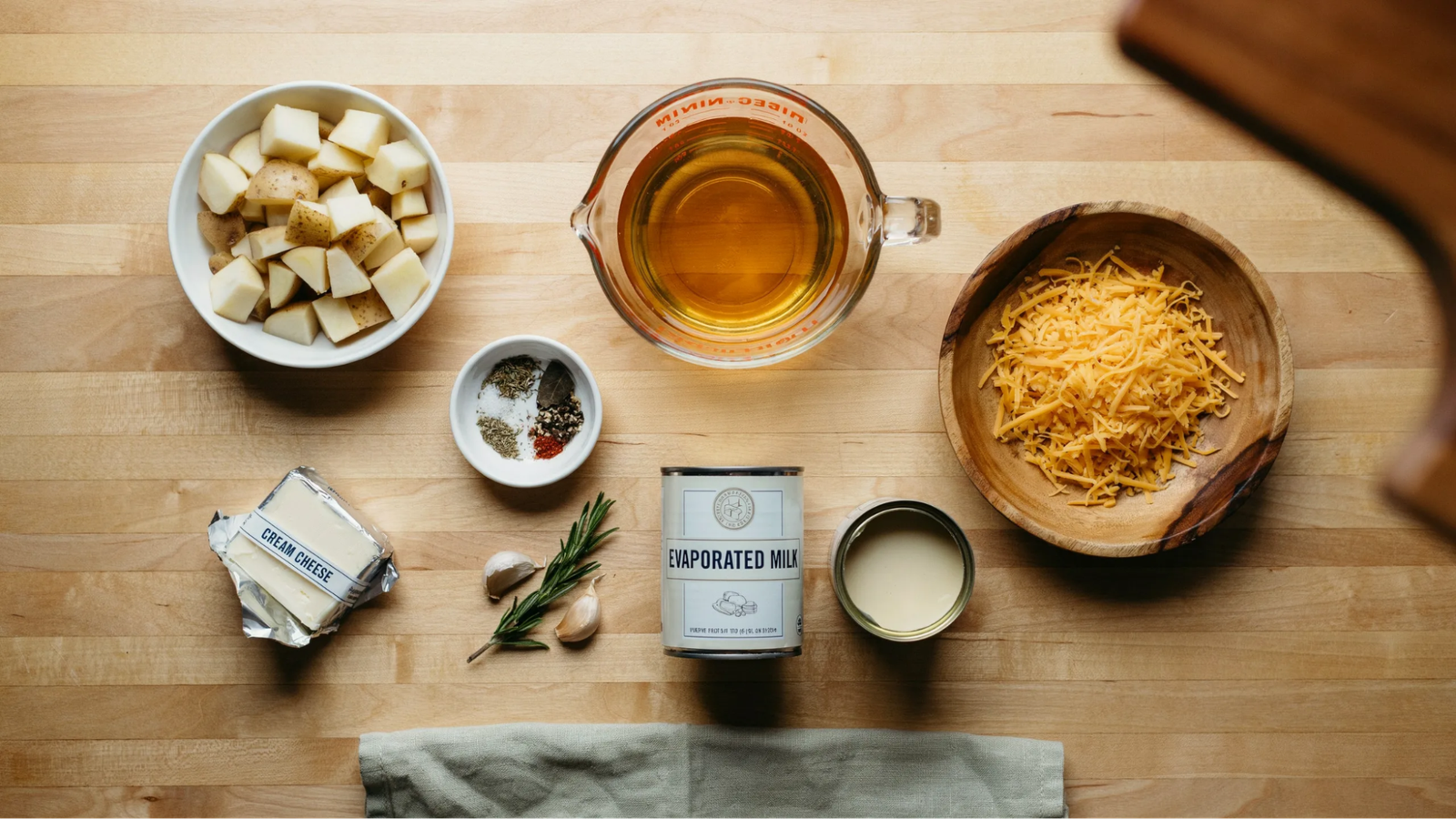 all ingredients for baked potato soup including potatoes broth cheese and seasonings arranged neatly on a kitchen counter.
