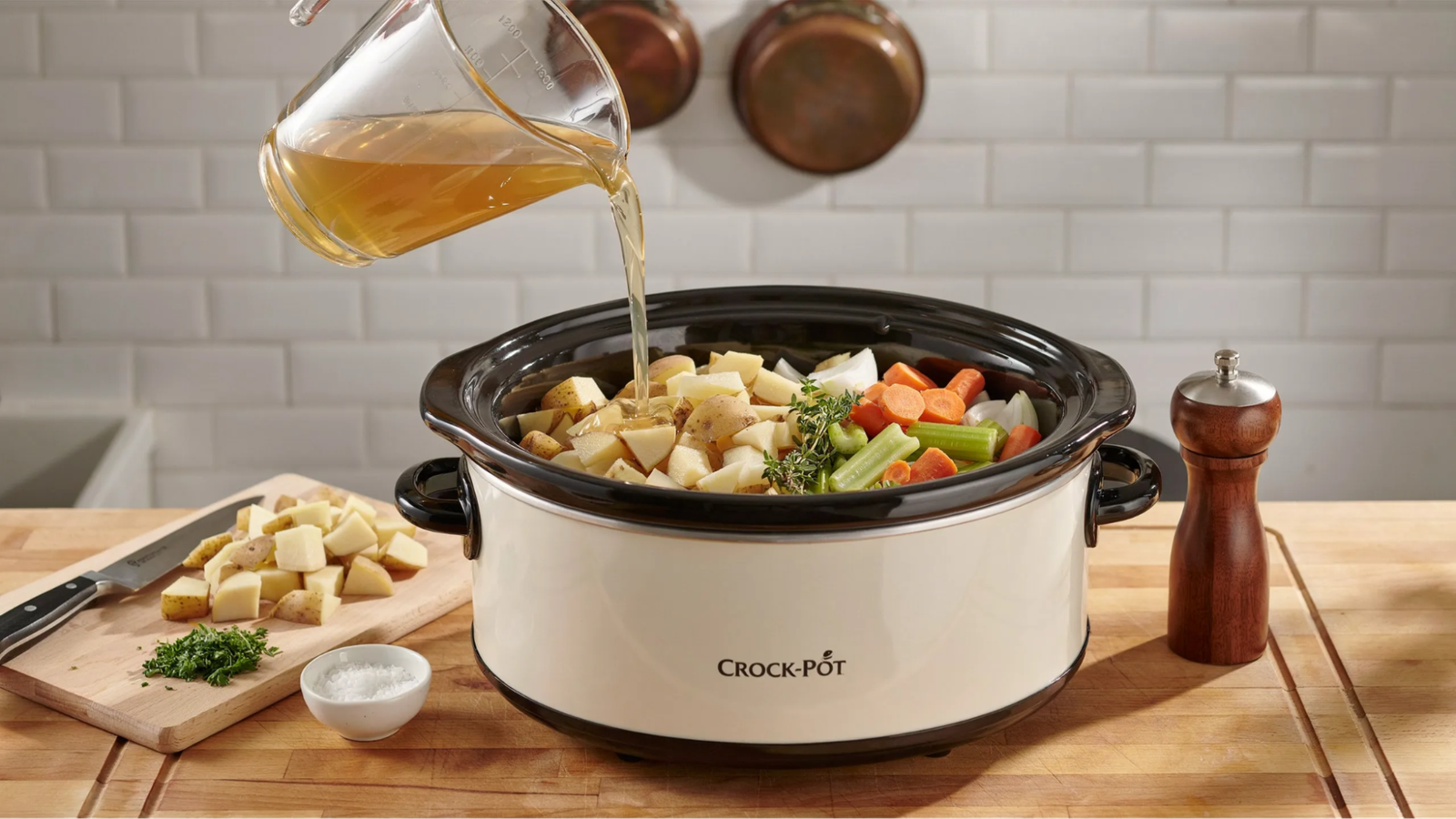 crock pot filled with potatoes, vegetables and broth ready for slow cooking.
